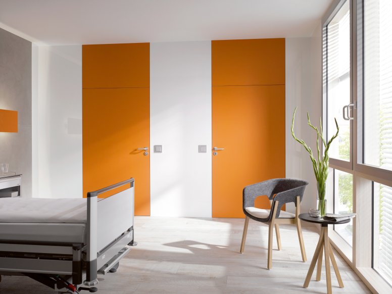 White hospital room with two orange doors fitted with a lever handle in the colour grey made of polyamide